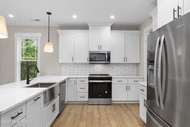kitchen featuring appliances with stainless steel finishes, white cabinets, light wood-style flooring, tasteful backsplash, and recessed lighting