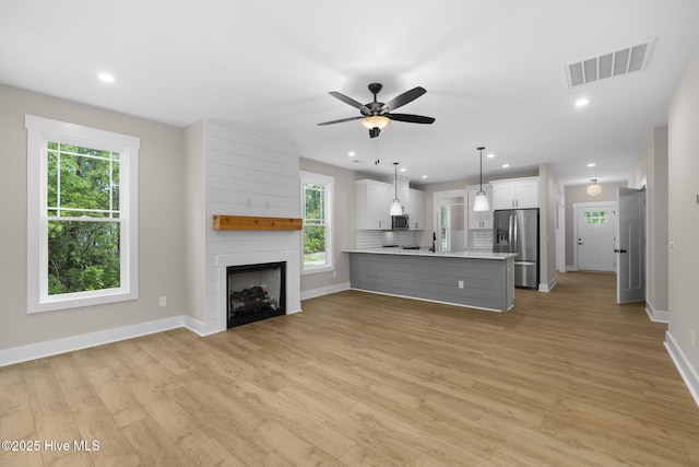 unfurnished living room featuring light wood-type flooring, baseboards, a large fireplace, a ceiling fan, and recessed lighting