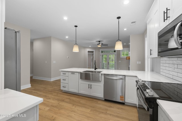 kitchen with appliances with stainless steel finishes, a sink, a ceiling fan, a peninsula, and white cabinets