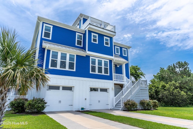 145 Whispering Pine Ln, Holly Ridge, NC 28445 - coastal inspired home featuring an attached garage, board and batten siding, a standing seam roof, a front yard, and stairs
