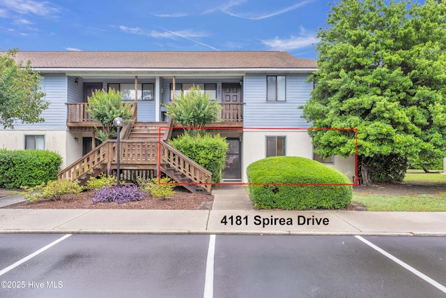 view of property featuring stairway and uncovered parking