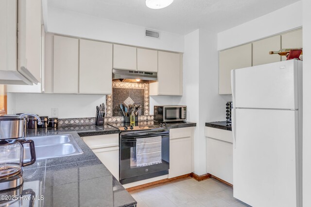 kitchen featuring freestanding refrigerator, under cabinet range hood, stainless steel microwave, black electric range oven, and a sink