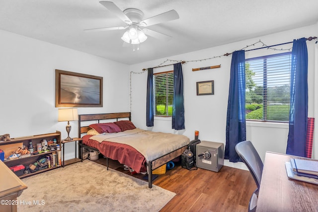 bedroom featuring wood finished floors, ceiling fan, an office area, and baseboards