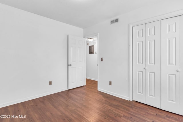 unfurnished bedroom with dark wood-style floors, baseboards, and a closet