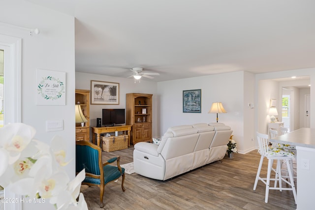 living room featuring ceiling fan, wood finished floors, and baseboards