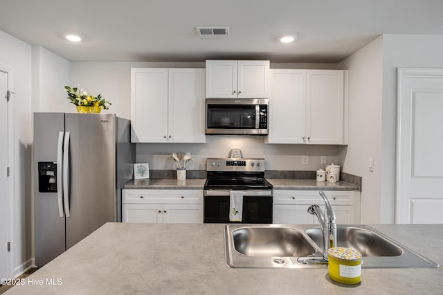 kitchen featuring appliances with stainless steel finishes, a sink, white cabinets, light countertops, and recessed lighting