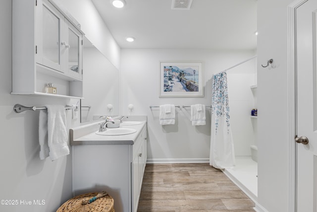 full bathroom featuring double vanity, curtained shower, wood finished floors, recessed lighting, and baseboards