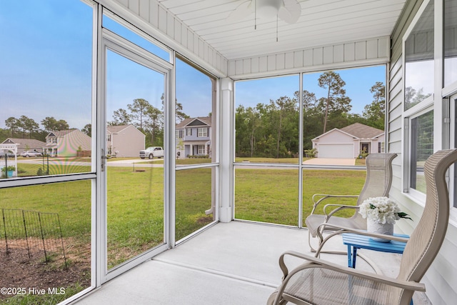 sunroom featuring ceiling fan and a residential view