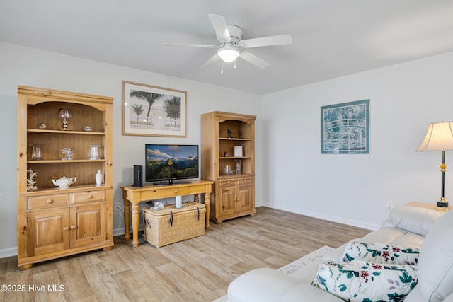 living area featuring light wood finished floors, a ceiling fan, and baseboards