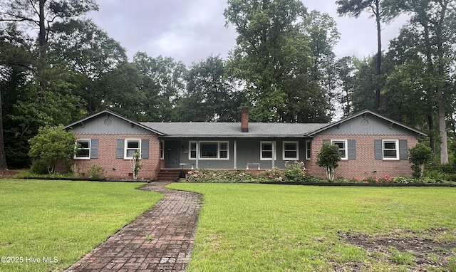 single story home featuring brick siding, a chimney, a front yard, and covered porch