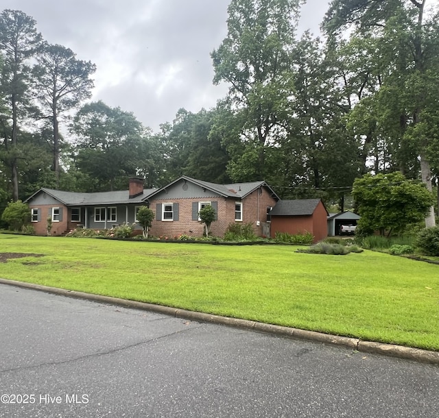 ranch-style house with a front lawn, view of scattered trees, a chimney, and brick siding