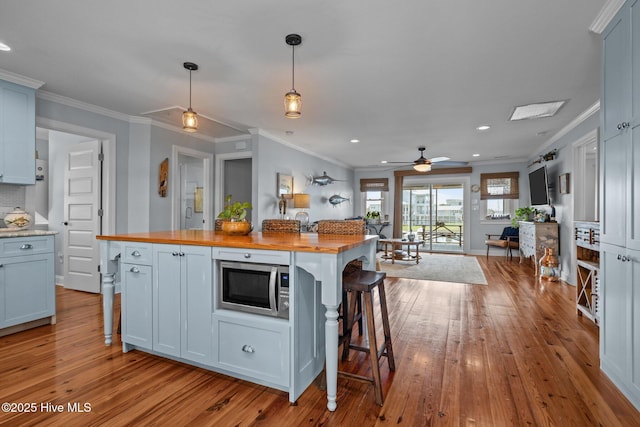 141 Bayview Blvd, Atlantic Beach, NC 28512 - kitchen featuring wooden counters, stainless steel microwave, hardwood / wood-style floors, a breakfast bar, and crown molding