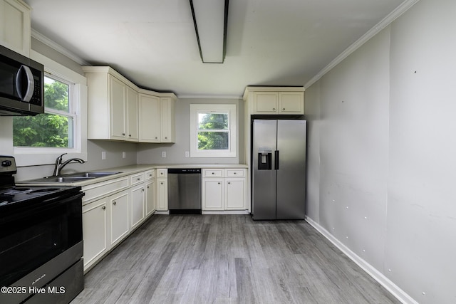 808 Green St, New Bern, NC 28560 - kitchen featuring appliances with stainless steel finishes, a sink, light wood-type flooring, light countertops, and crown molding