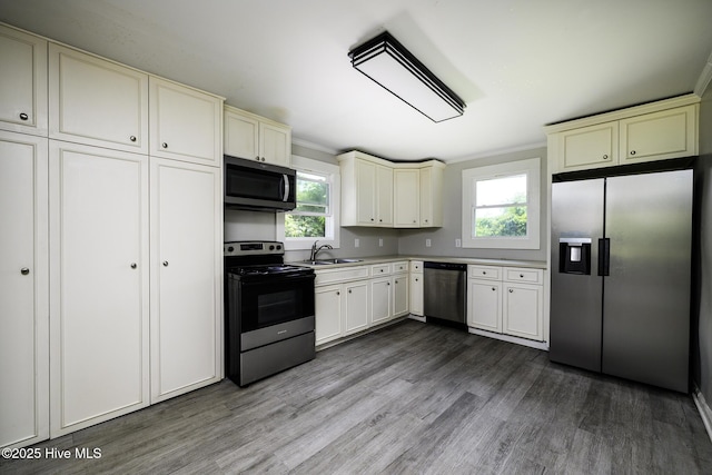 808 Green St, New Bern, NC 28560 - kitchen with stainless steel appliances, cream cabinetry, a sink, dark wood-style flooring, and ornamental molding