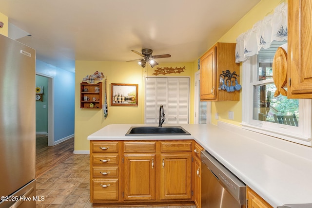 kitchen featuring appliances with stainless steel finishes, a sink, a peninsula, ceiling fan, and light countertops