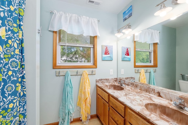 bathroom with double vanity, toilet, and baseboards