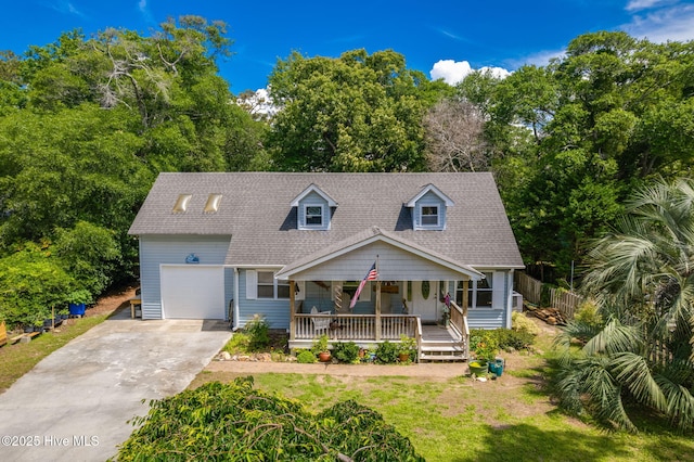 cape cod-style house with covered porch, a garage, concrete driveway, view of scattered trees, and a shingled roof