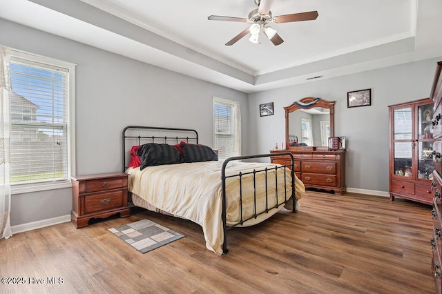 312 Hughes Ln, Jacksonville, NC 28546 - bedroom with a tray ceiling, light wood-style flooring, baseboards, ornamental molding, and ceiling fan
