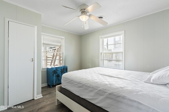 bedroom featuring ornamental molding, dark wood-type flooring, multiple windows, and ceiling fan