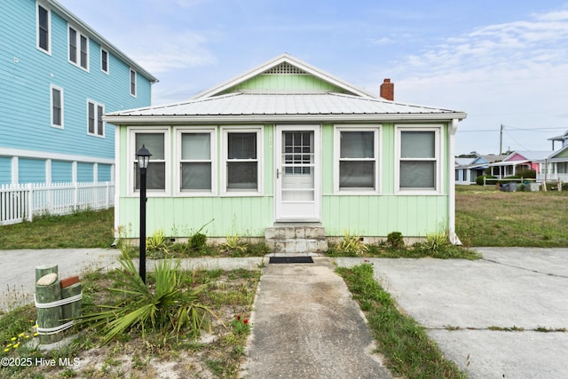 view of front of property featuring entry steps, a chimney, fence, metal roof, and crawl space