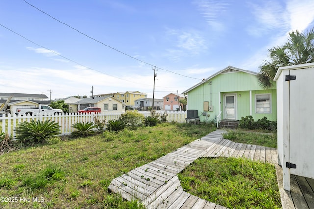 view of yard featuring fence, central air condition unit, and a residential view