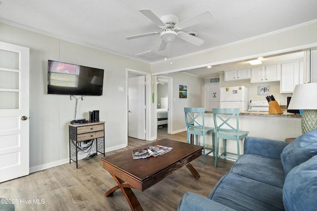 living area featuring crown molding, a ceiling fan, wood finished floors, and baseboards