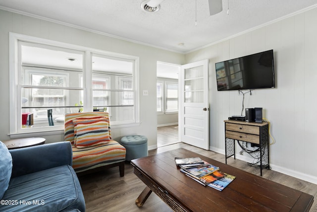living area featuring crown molding, wood finished floors, ceiling fan, a textured ceiling, and baseboards