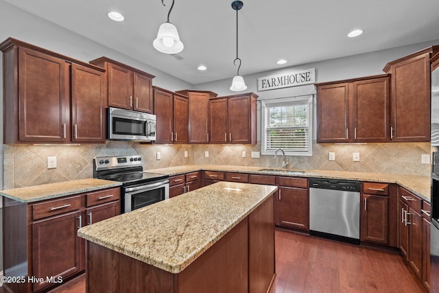 kitchen with appliances with stainless steel finishes, a sink, light stone countertops, dark wood-type flooring, and decorative light fixtures