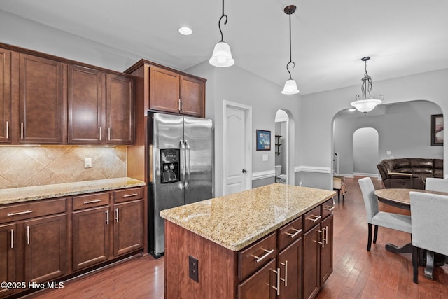 kitchen featuring stainless steel fridge, arched walkways, dark wood finished floors, decorative backsplash, and recessed lighting