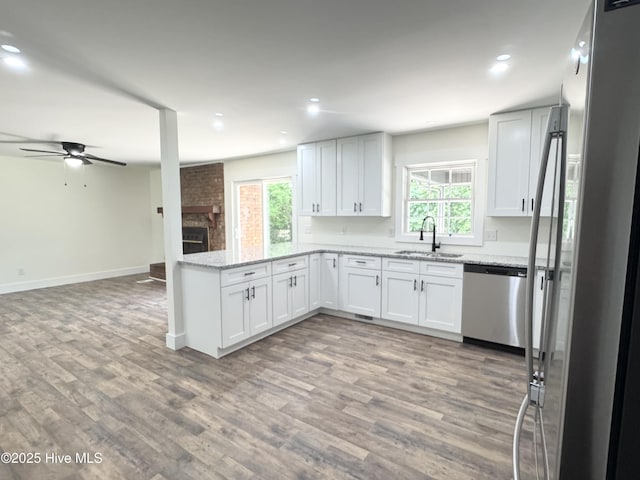 200 Colonial Ave, Clinton, NC 28328 - kitchen with appliances with stainless steel finishes, a peninsula, ceiling fan, a brick fireplace, and wood finished floors