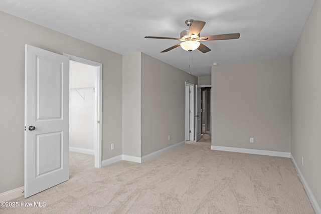 unfurnished bedroom with carpet floors, a spacious closet, a closet, and baseboards