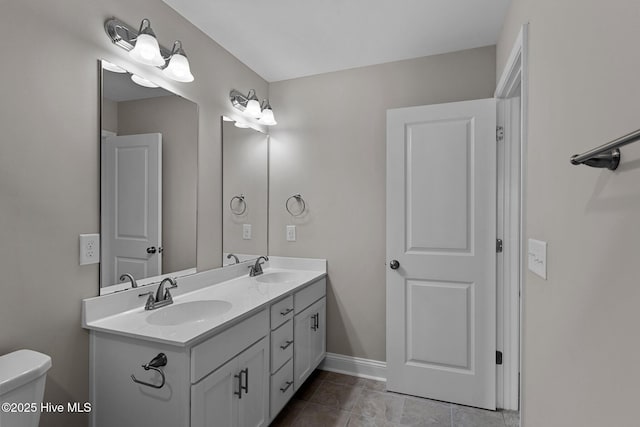 full bath with toilet, double vanity, and baseboards