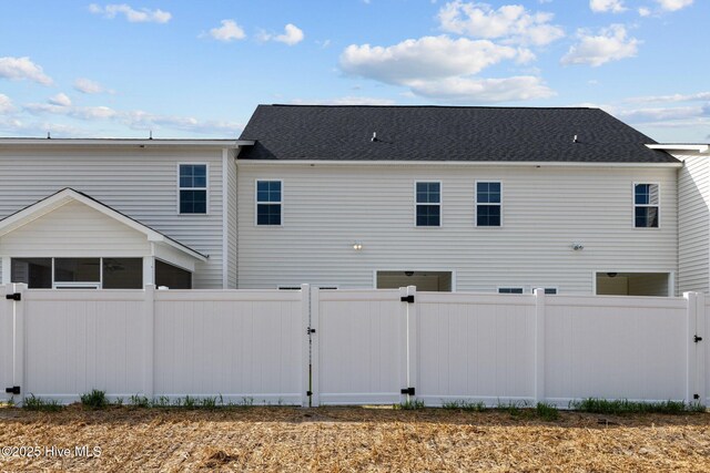 rear view of house with fence and a sunroom