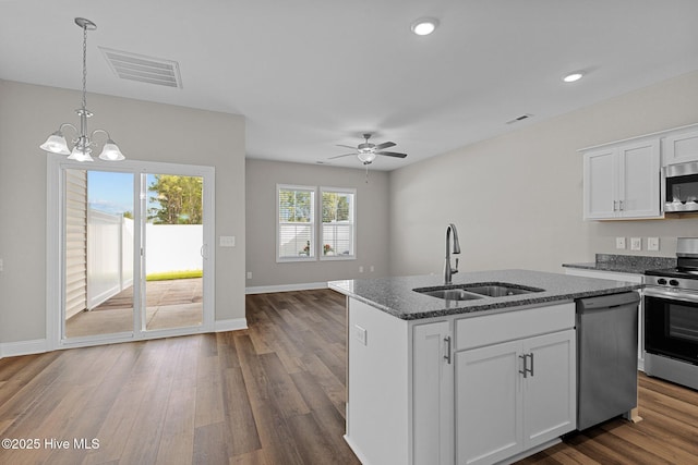 kitchen featuring appliances with stainless steel finishes, a sink, dark stone counters, a chandelier, and dark wood-style floors