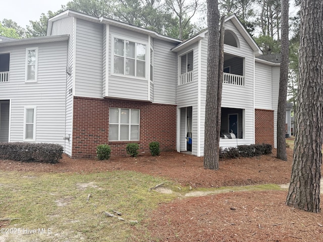 view of front of home featuring brick siding and a balcony