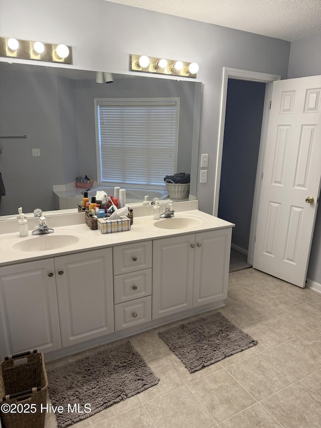 bathroom featuring double vanity, tile patterned floors, and a textured ceiling