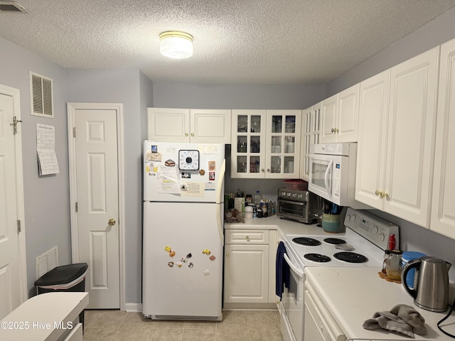 kitchen featuring white appliances, light countertops, a textured ceiling, white cabinets, and glass insert cabinets