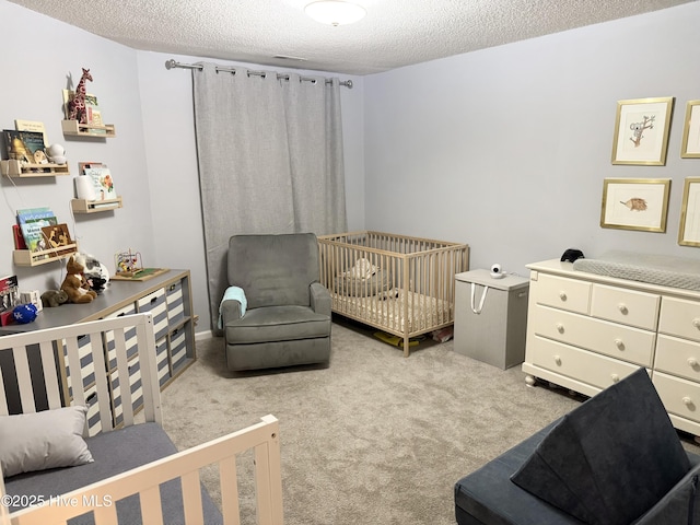 carpeted bedroom featuring a textured ceiling and a nursery area