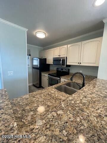 kitchen featuring stainless steel appliances, ornamental molding, a sink, white cabinetry, and stone countertops