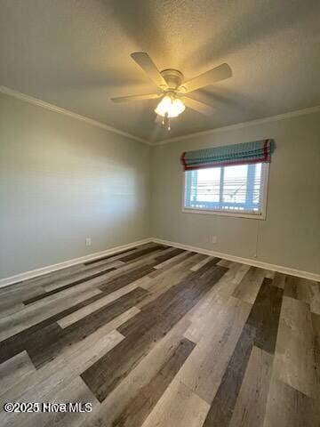 empty room featuring crown molding, ceiling fan, wood finished floors, and baseboards