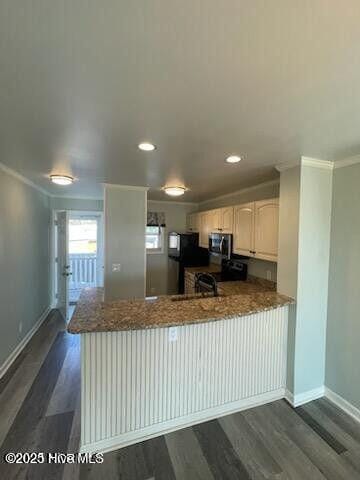 kitchen featuring stainless steel microwave, a peninsula, crown molding, dark wood finished floors, and baseboards