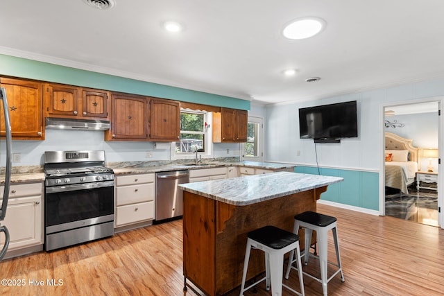 212 Park Ave, Southport, NC 28461 - kitchen with stainless steel appliances, crown molding, under cabinet range hood, light wood-type flooring, and a kitchen island
