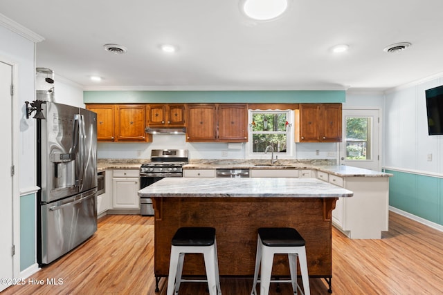212 Park Ave, Southport, NC 28461 - kitchen featuring appliances with stainless steel finishes, a sink, under cabinet range hood, light wood-style flooring, and ornamental molding