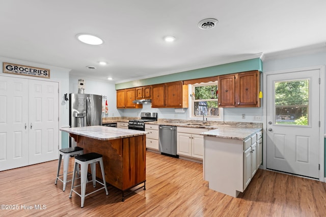 212 Park Ave, Southport, NC 28461 - kitchen featuring appliances with stainless steel finishes, crown molding, a sink, under cabinet range hood, and light wood-type flooring