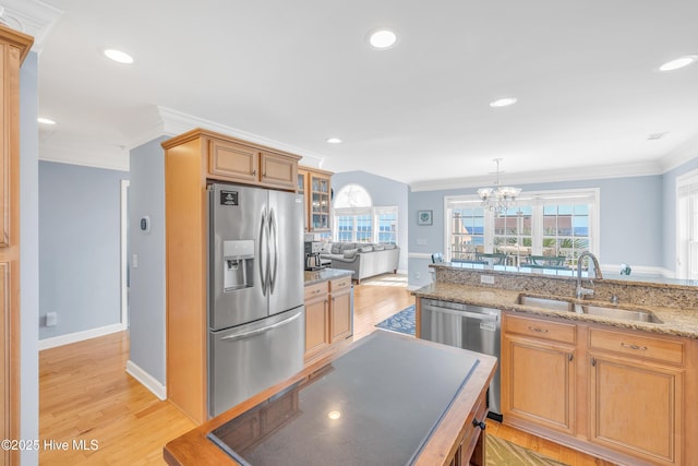 308 E Beach Dr, Oak Island, NC 28465 - kitchen featuring appliances with stainless steel finishes, a sink, ornamental molding, a chandelier, and light stone countertops