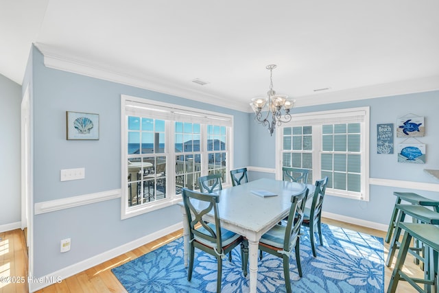 308 E Beach Dr, Oak Island, NC 28465 - dining space with a chandelier, baseboards, crown molding, and wood finished floors