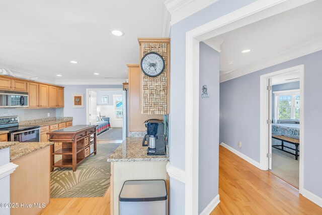 308 E Beach Dr, Oak Island, NC 28465 - kitchen featuring appliances with stainless steel finishes, crown molding, light wood-type flooring, decorative backsplash, and light stone counters