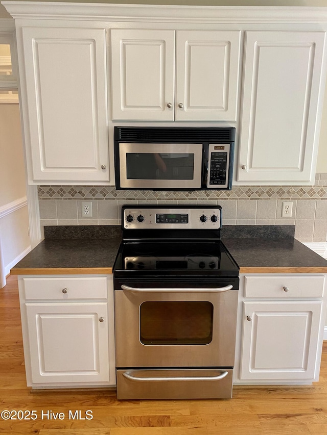 kitchen featuring stainless steel appliances, dark countertops, and white cabinets