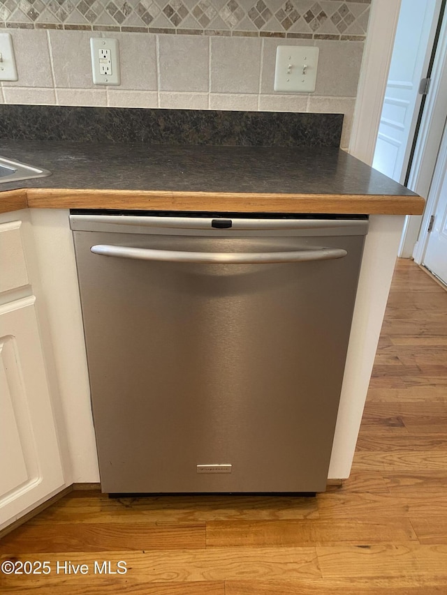 kitchen view of dishwasher, dark countertops, and decorative backsplash