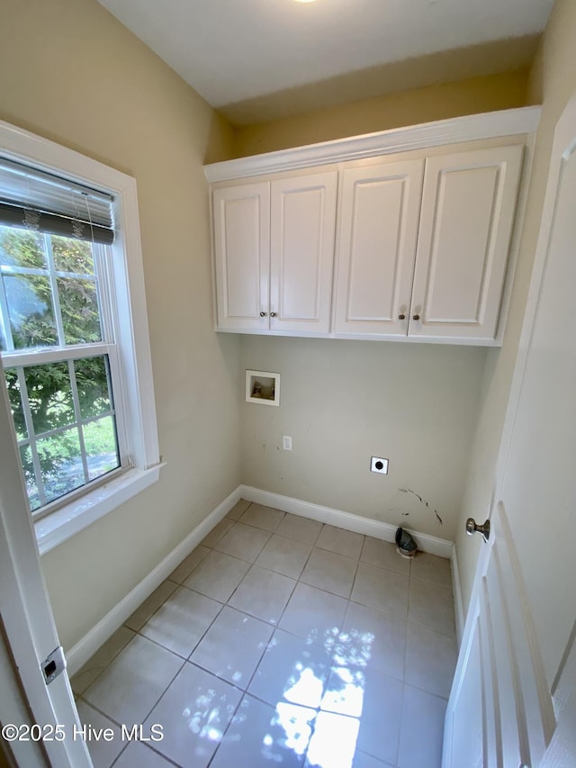 clothes washing area with hookup for a washing machine, cabinet space, hookup for an electric dryer, light tile patterned floors, and baseboards